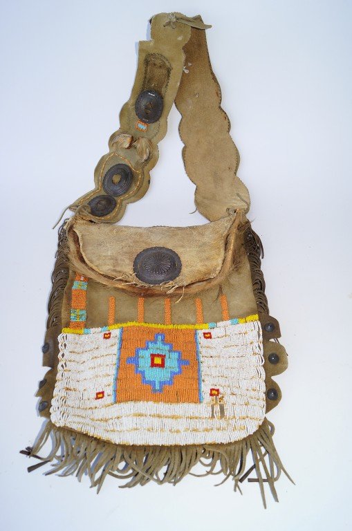 Intricate Beadwork and Leather Bag: Different metal applications to the strap and pouch cover. Horse hair trim. 32"L. x 13"W.