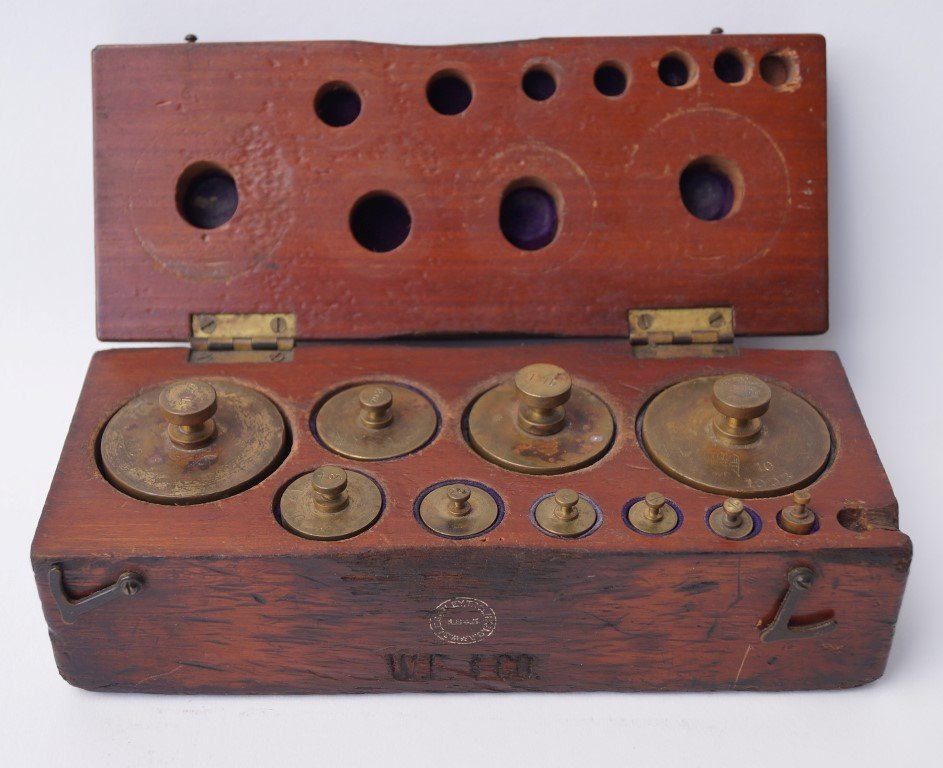 Wells Fargo Brass Weights in Wooden Box: Wells Fargo & Co. carved into the top. Iron bail handle 9" L x 3 1/2" D x 3" H.