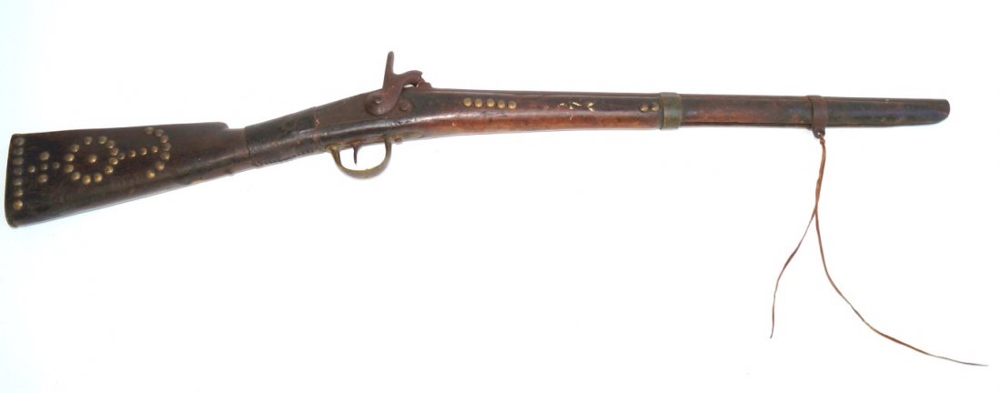 Percussion Rifle: 69 Calibre. Carbine. 23" barrel. Percussion Smooth bore. Indian owned. Brass tack decoration patterns throughout stock. Three painted cross like decorations at the top. C. S. is carved in the off 