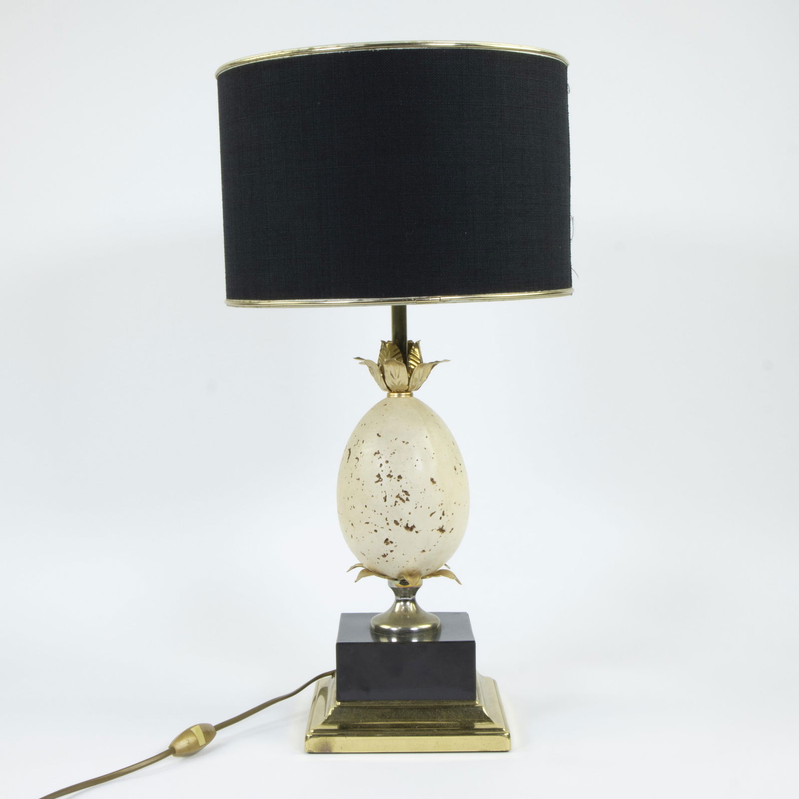 House BARBIER, table lamp model Oxford decorated with an egg in travertine and foliage in gilded: House BARBIER, table lamp model Oxford decorated with an egg in travertine and foliage in gilded metal, the whole resting on a square base in black tinted wood and brass, 1970sMaison BARBIER, tafellam