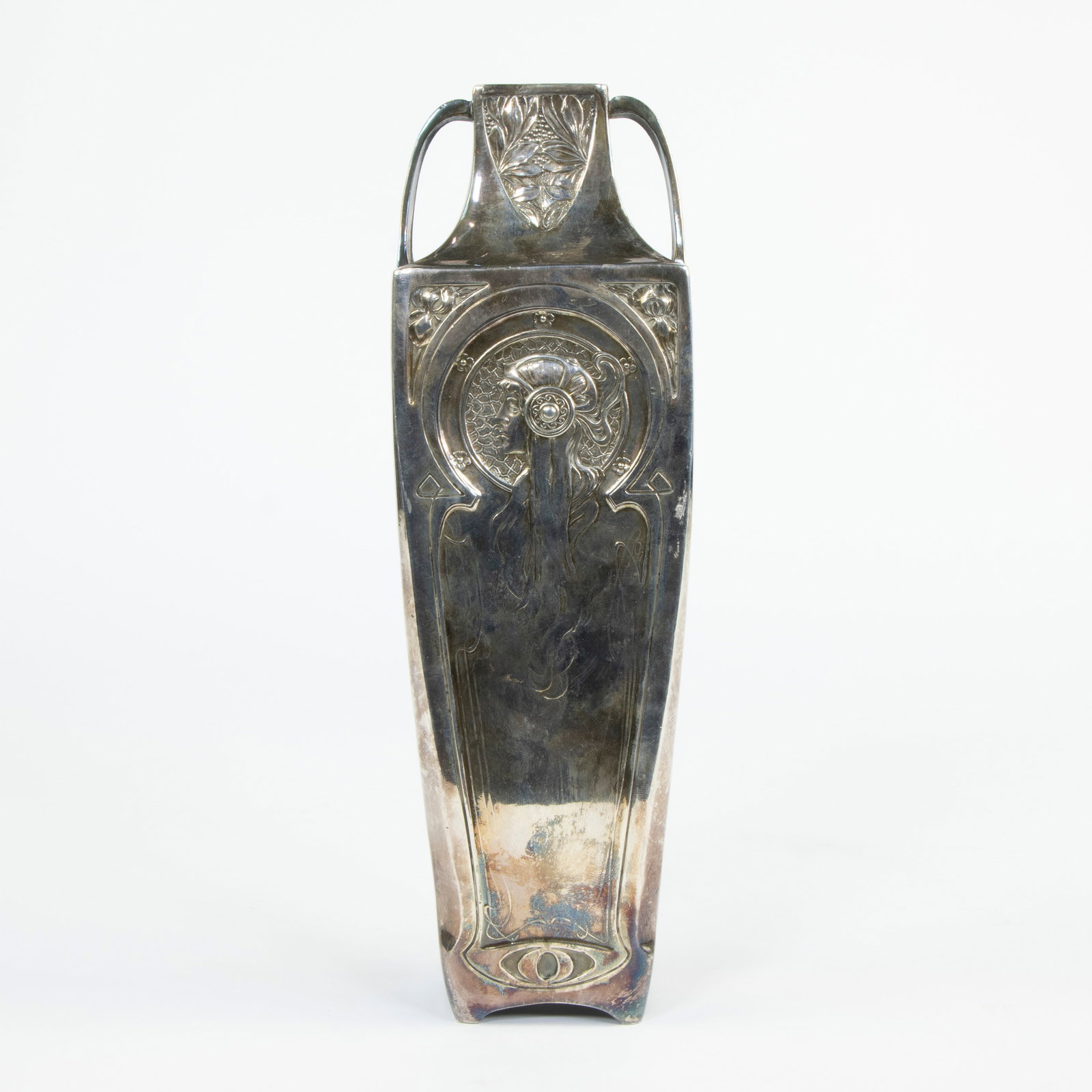 A silver-plated vase with relief decoration of two Byzantine female heads in profile and with laurel: A silver-plated vase with relief decoration of two Byzantine female heads in profile and with laurel and iris blossoms, after Alphonse Mucha, circa 1900Een verzilverde vaas met reli?fversiering van tw