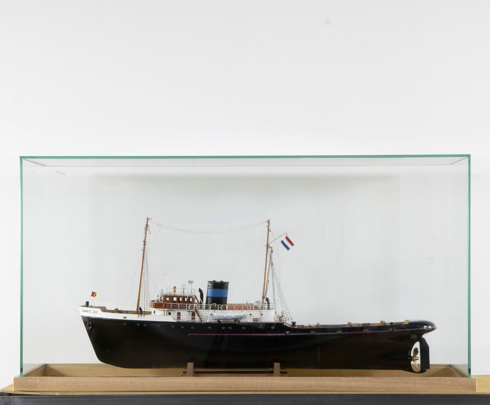 Finely crafted wooden scale model of the Dutch tugboat Zwarte Zee in a glass display case with: Finely crafted wooden scale model of the Dutch tugboat Zwarte Zee in a glass display case with wooden baseFijn vervaardigd houten schaalmodel van de Nederlandse sleepboot Zwarte Zee in een glazen vitr