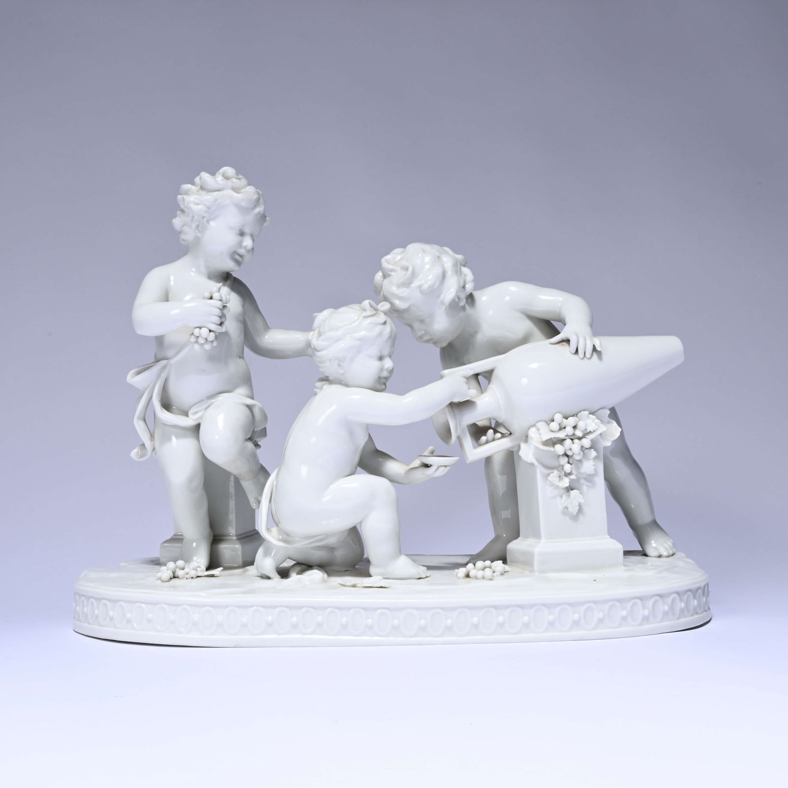 Porcelain group of three putti playing with a wine amphora, Volkstedt, marked: Porcelain group of three putti playing with a wine amphora, Volkstedt, markedPorseleinen groep van drie putti's spelend met wijnamfoor, Volkstedt, gemerkt37 x 19.5 x 27 cm