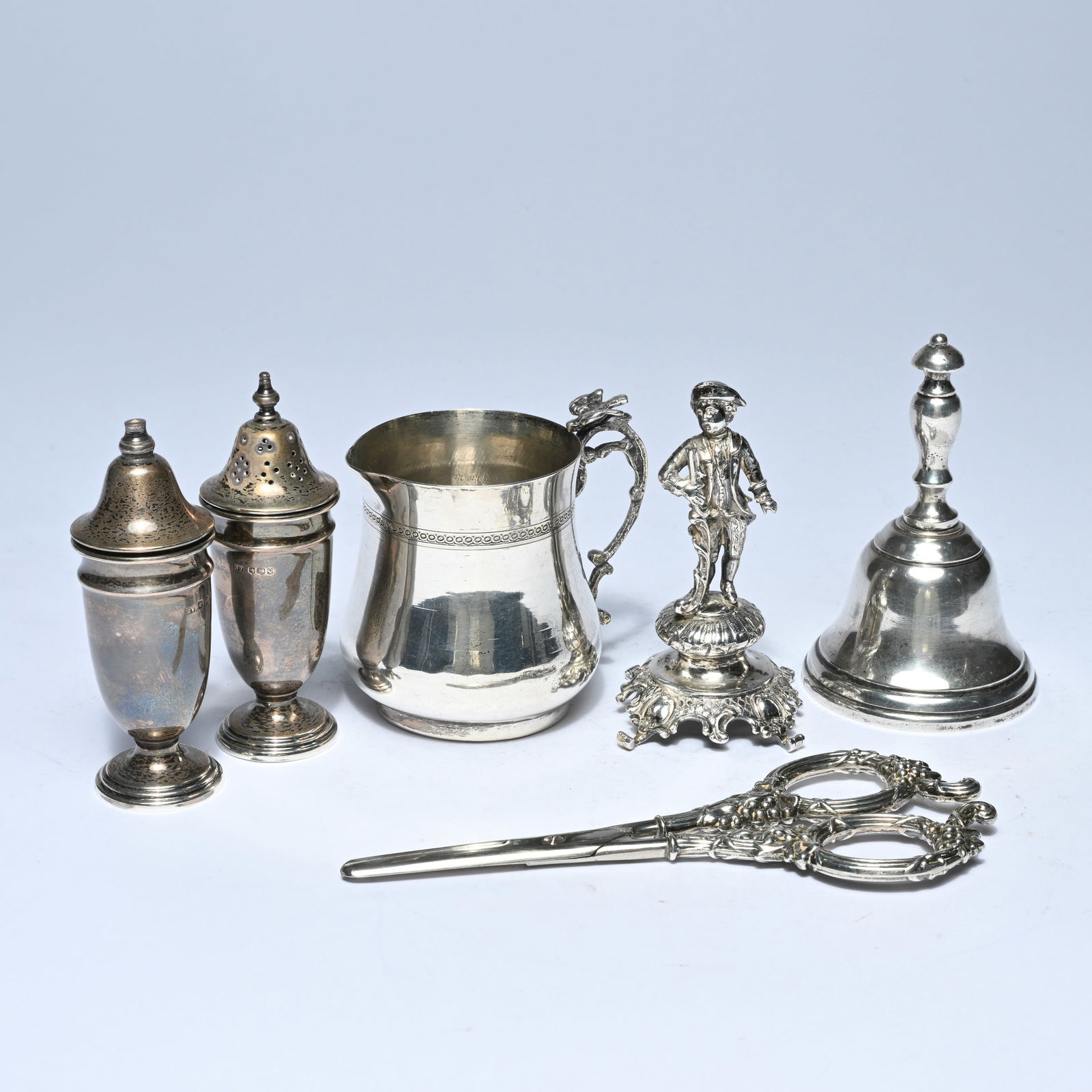 Collection of silver consisting of pepper and salt shakers, jugs, bell, bowl and statue of a boy, (1 of 9)