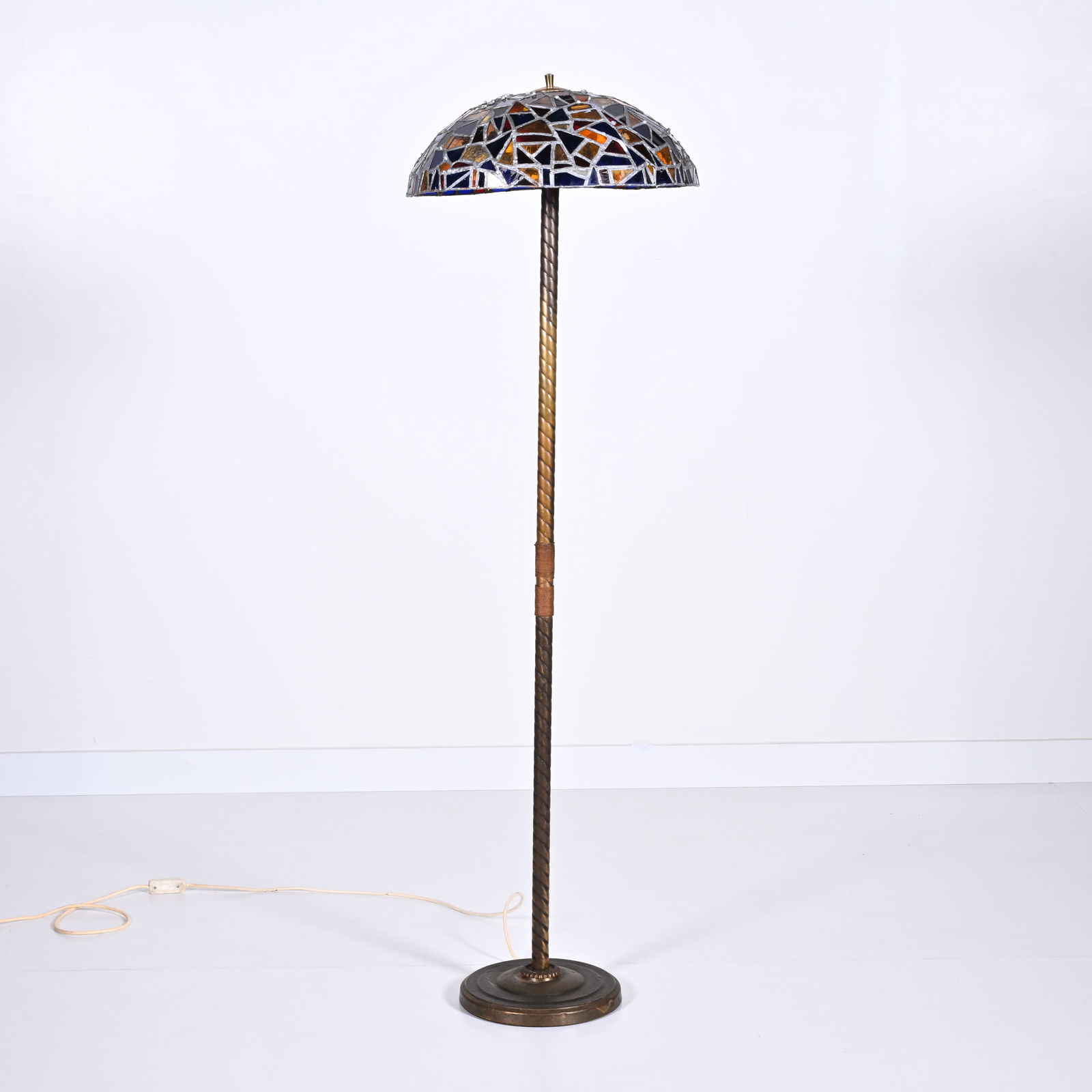 Stained glass mosaic lamp on a tall brass stand, circa 1910, French: Stained glass mosaic lamp on a tall brass stand, circa 1910, FrenchGlas-in-lood mozaiëklamp op een hoge messing voet, circa 1910, FransH 148 cm