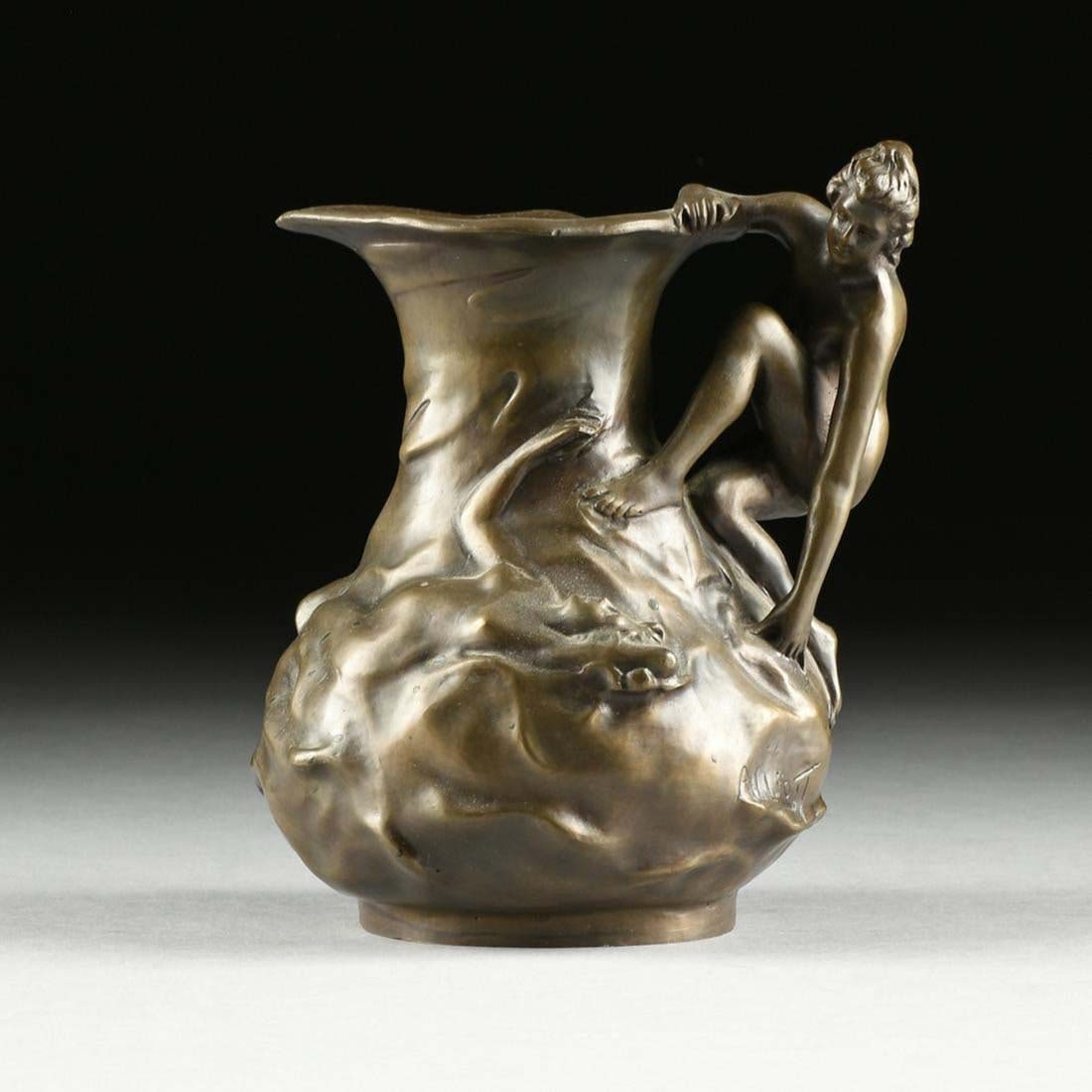 After Lucien Charles Edouard Alliot (French 1877-1967) A Bronze Figural Ewer: After Lucien Charles Edouard Alliot (French 1877-1967) A Bronze Figural Ewer in an Art Nouveau style, the lightly patinated brown rounded rim and everted spout tapering to a short circular neck on a b