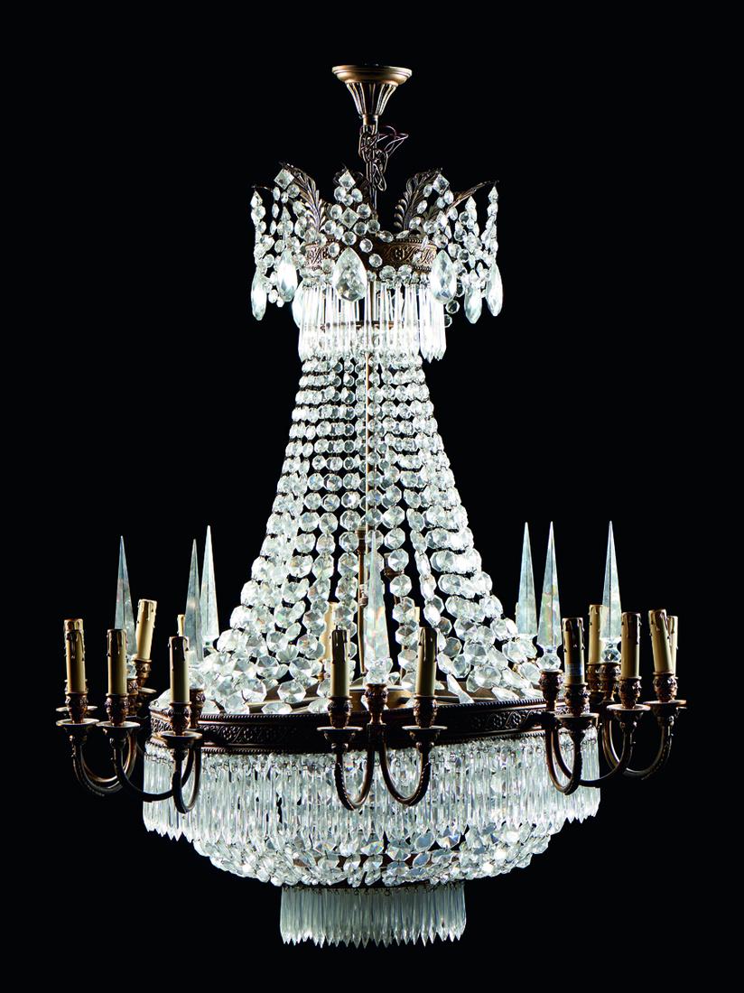 Lustre de 20 lumes em cristal: Lustre de vinte lumes, em metal, com pingentes em cristal. Corpo em forma de chuveiro encimado por plumas estilizadas com fitas de lágrimas e pingentes. Braços curvos decorados com elementos