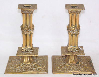 A Pair of Charles II Style Brass Candlesticks: A Pair of Charles II Style Brass Candlesticks. Circa 19th Century. Fluted square cluster-columns, broad socles cast with flowers and foliage, domed bases with putti amonngst further flowers and