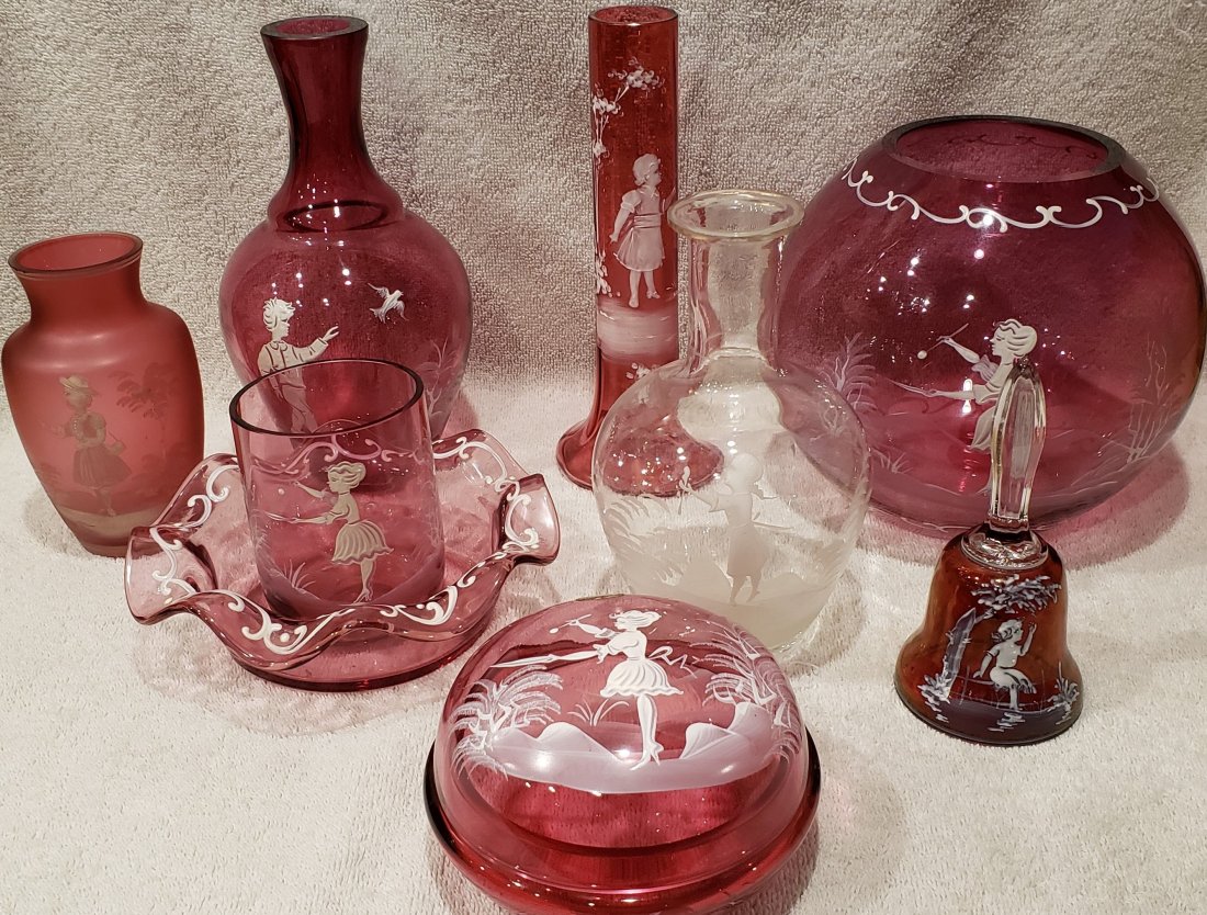 Collection of Mary Gregory Cranberry Glass: 9 Pieces total. 1 Vase is clear glass. The other 8 pieces are Cranberry glass. Tallest piece is 8 1/4" tall. Widest piece is 7" wide. Dresser dish retains original "Bohemia Crystal Czechoslovakia" lab
