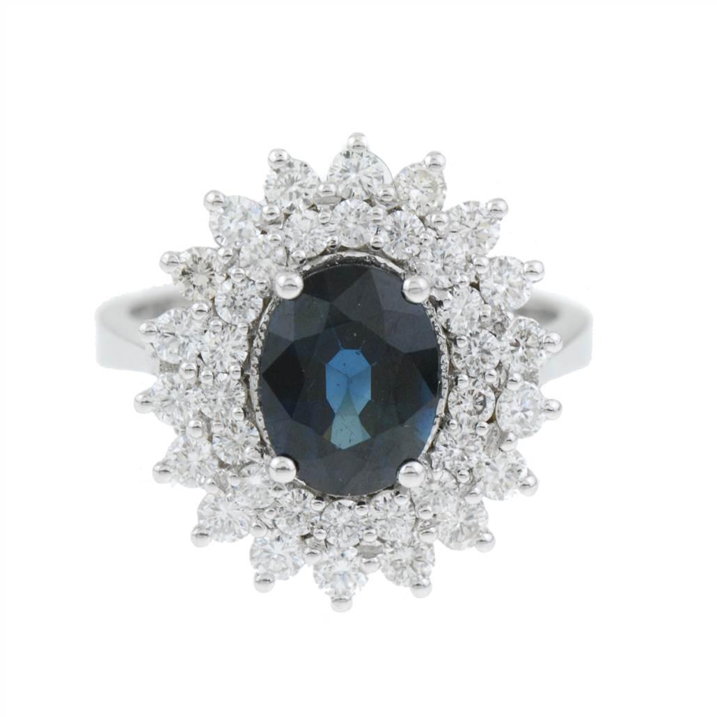 DIAMOND AND SAPPHIRE ROSETTE RING: White gold with brilliant cut diamonds, total weight approx. 1.85 ct. and central oval cut sapphire, approx. weight 2 ct. Band 17.5 mm. 7.1 gm.