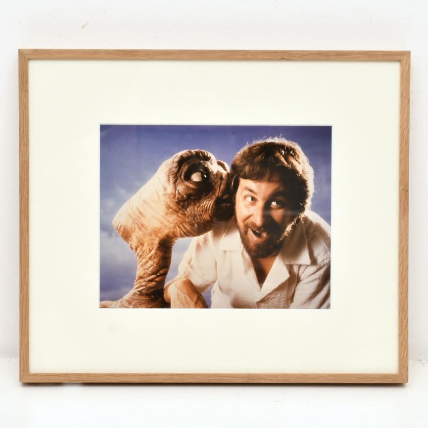 Bruce McBroom (1939). E.T. the Extra-Terrestrial, 1982.: Colour photograph. Promotional photograph for the film ‘E.T., the Extra-Terrestrial’, directed by Steven Spielberg in 1982, showing the main character, E.T., kissing the director. 20 x 25.5 cm; 35