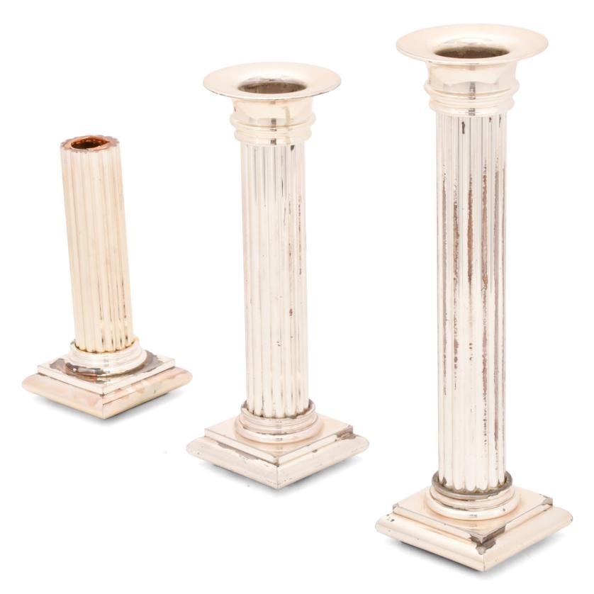 Set of three candlesticks, 20th century.: Silvery metal. Column-shaped.The smallest one has a loss on the bottom. 18.5 x 8.5 x 8.5 cm (the smallest)?31 x 8.5 x 8.5 cm (the largest).