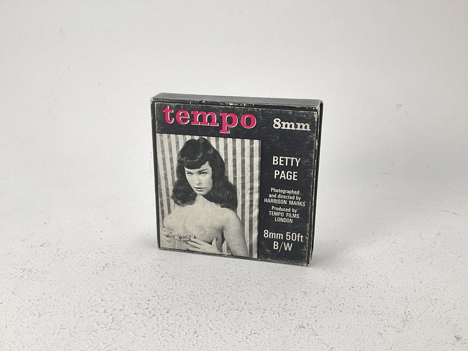 A 8mm Tempo Film of Betty Page,: Packaging reads ' Betty Page, Photographed and Directed by Harrison Marks, Produced by Tempo Films London' X.11 8mm 50ft B/W Film appears to be in VG condition, (Qty: 1)