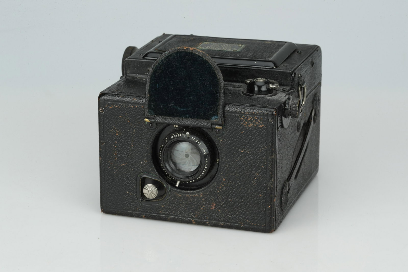A Houghton Ensign Focal Plane Roll Film Reflex Camera,: black, body G, some wear to outer paint, shutter untested, with Aldis Uno Anastigmat 4" f/4.5 lens, optics F-G, some haze, coating issues, and fungus present, (Qty: 1)