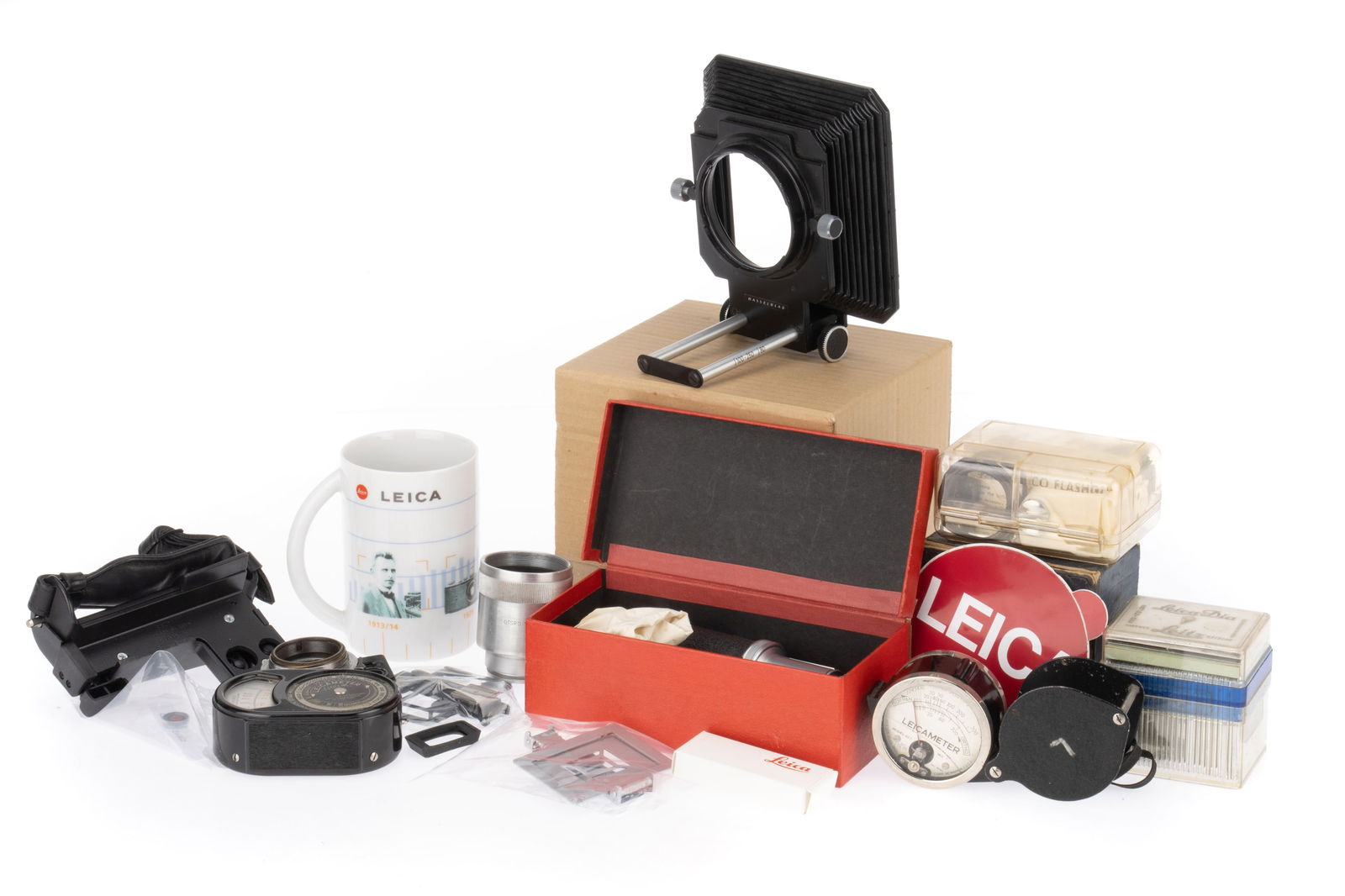 A Selection of Leitz Wetzlar Photographica,: to include Leicameters, fan flashes, Pro-Colour metal slides, a Leica mug and penknife, and a Hasselblad bellows.