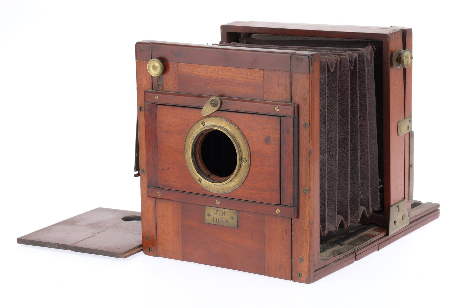 A "J.H. 1884" Half Plate Tailboard Camera Body: A "J.H. 1884" Half Plate Tailboard Camera Body with a brass plate engraved "J.H. 1884", large tear in square-cornered bellows, ground glass focusing screen intact, overall condition P-F