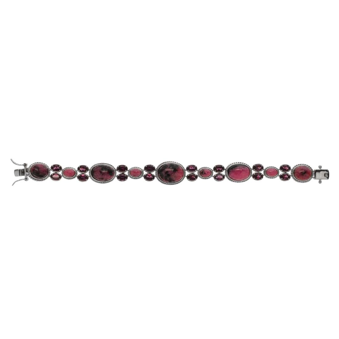 Sterling Silver Rhodonite & Garnet Bracelet: Genuine sparkling rhodolite and rhodolite garnet gemstones adorn this lovely design from the Pangea Mines Treasured Gems Collection. Crafted in gleaming rhodium over sterling silver with a convenient,