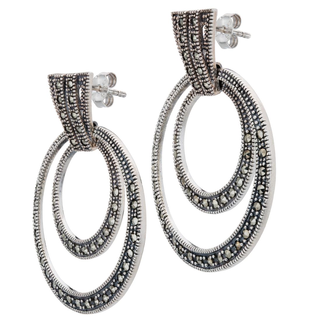 Sterling Silver Marcasite Orbital Hoop Earrings: Sport a dramatic look from Addison Lane’s Weekend Collection! Big, bold orbital hoops are gracefully styled in oxidized sterling silver and lavishly adorned with sparkling marcasite to create a 