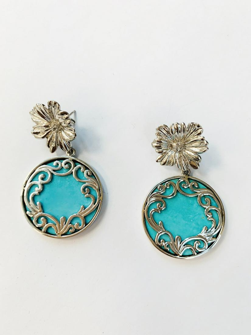Silver Turquoise Scrollwork Overlay Flower Earring: Metal: Rhodium over sterling silver Stone Information: Gemstone Choice: Two round 26mm stabilized and compressed Kingman turquoise cabochons White Zircon: Two round modified-brilliant cut 2mm Setting 