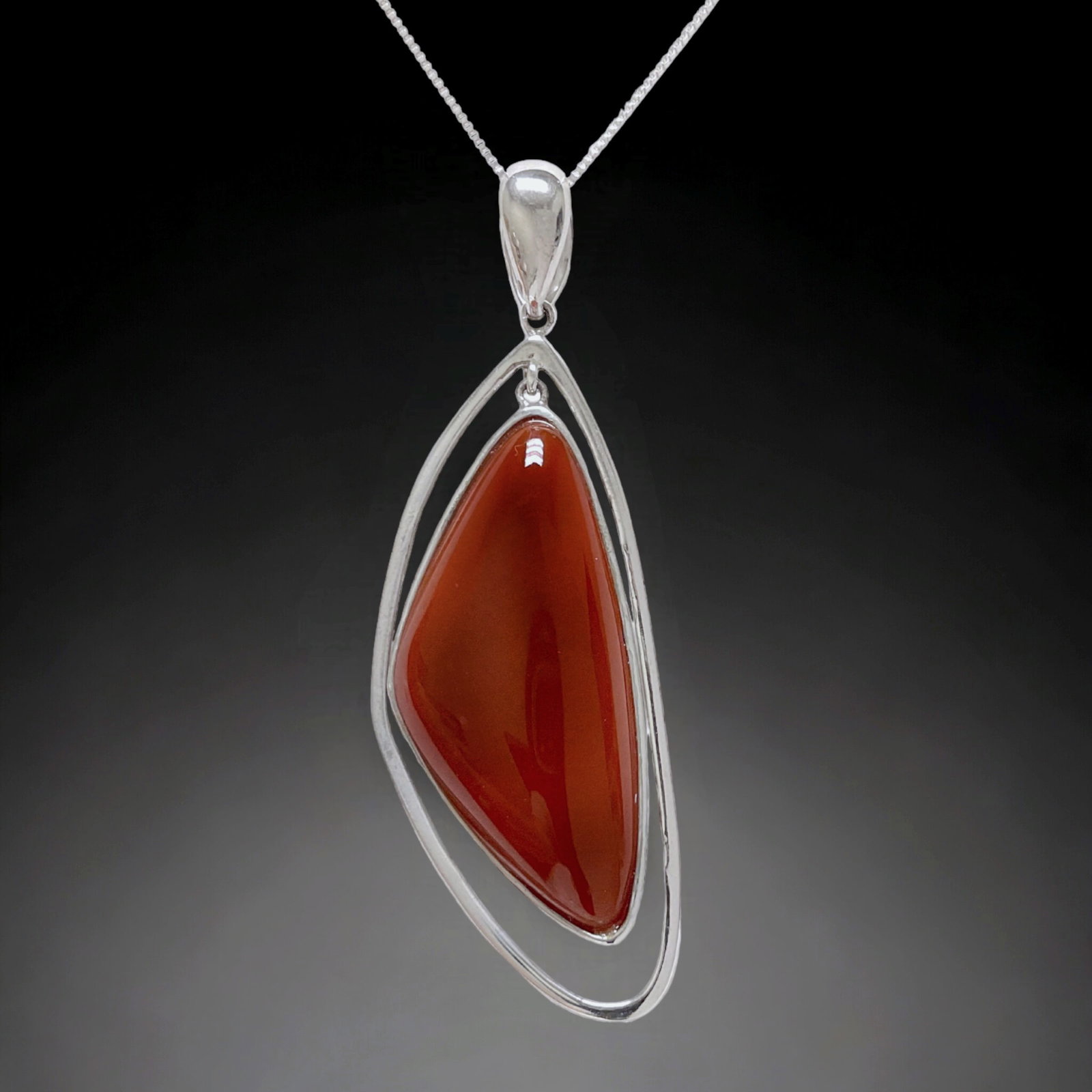 Modern Carnelian Pendant in Sterling Silver with Chain: Product Details Item: Pendant Metal: Sterling Silver Gemstone: Carnelian Approximate Measurements: Pendant: 66.3 mm X 23.1 mm Ring Size: Not Applicable Chain Length: 18" Chain Metal: Ste