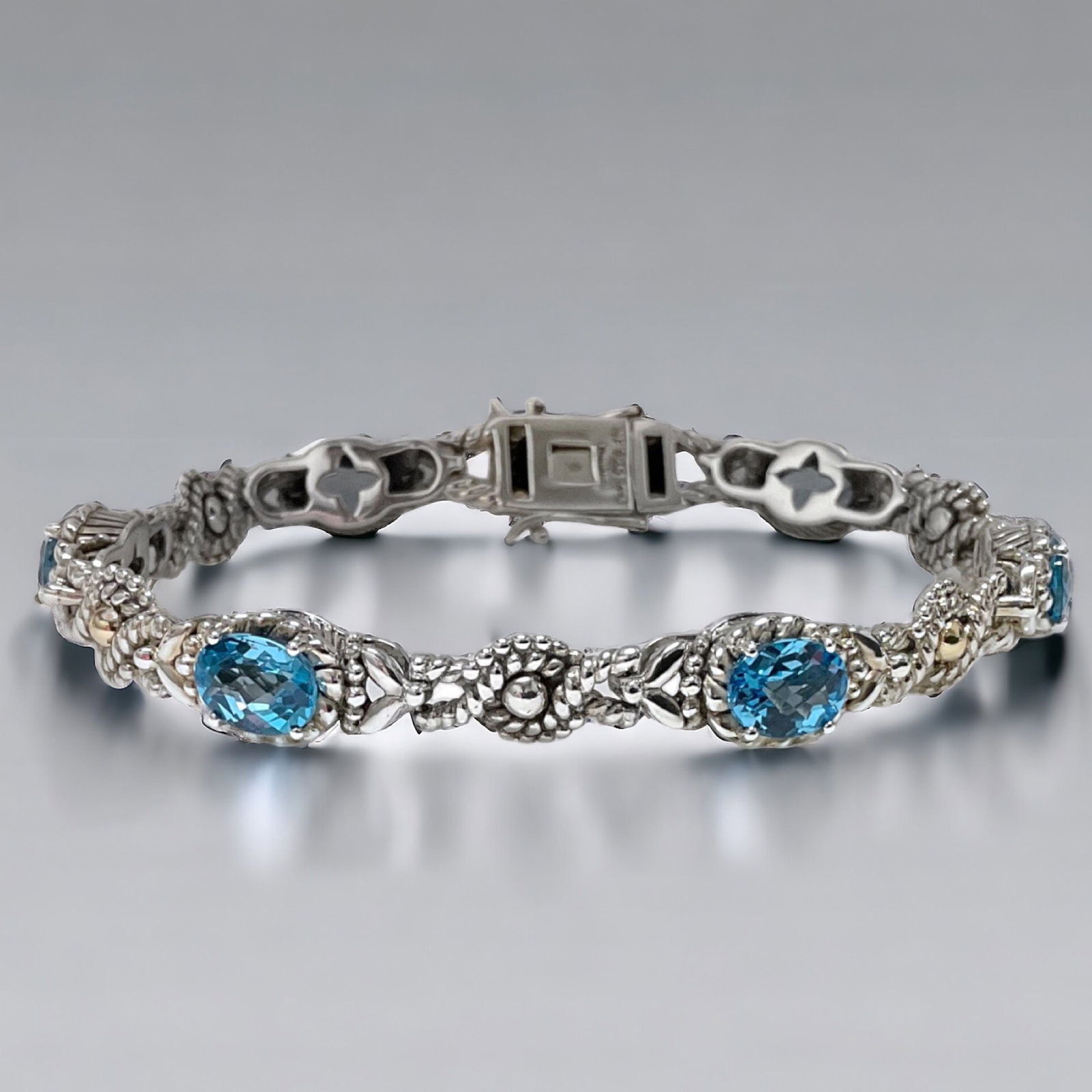 Sophisticed Swiss Blue Topaz Bracelet set in 14K Gold & Sterling Silver: Product Details Item: Bracelet Metal: 14K Gold & Sterling Silver Gemstone: Swiss Blue Topaz Approximate Measurements: 7.5" X 8.4 mm Ring Size: Not Applicable Chain Length: Not Applicable