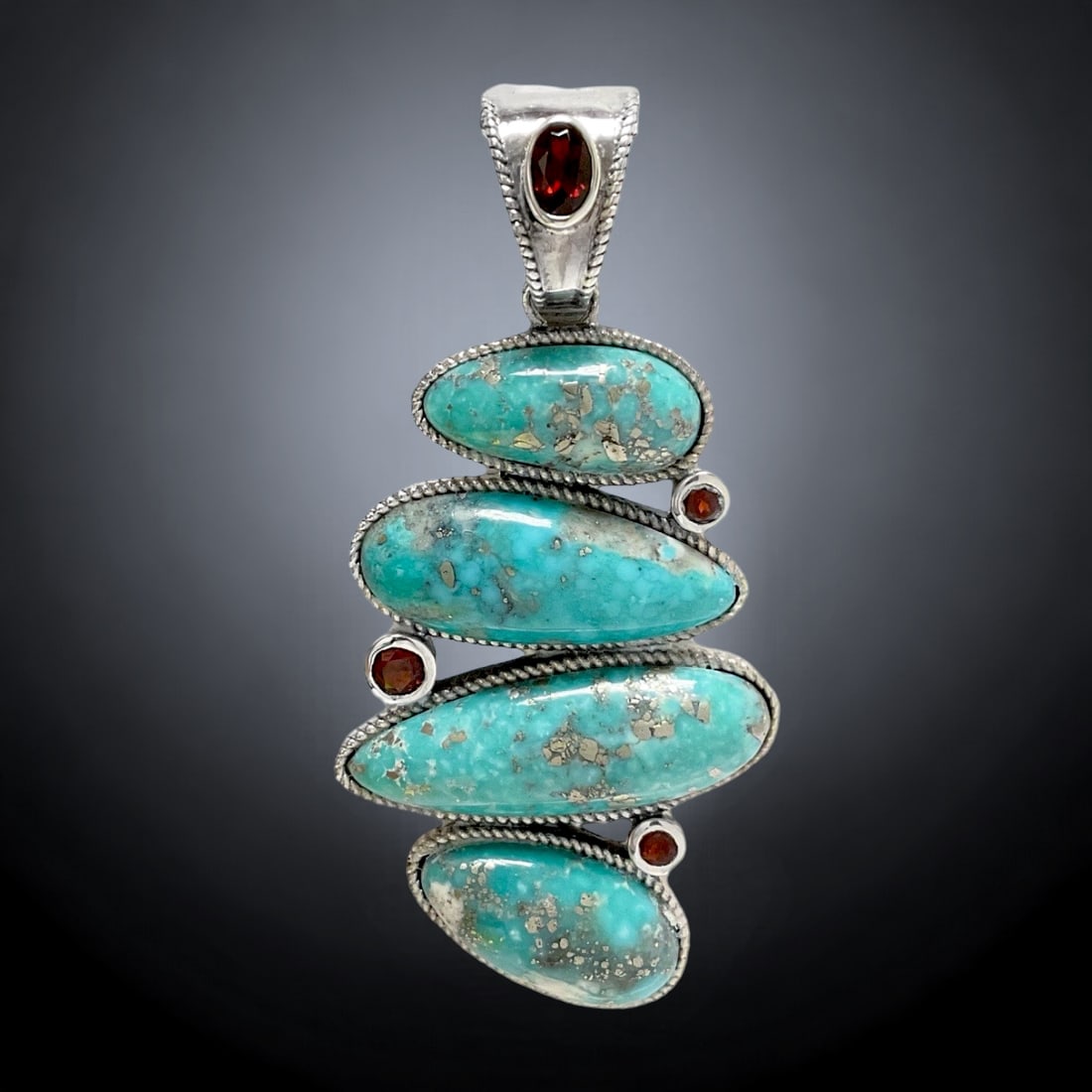 Campo Frio Turquoise Pendant combined with Garnet and crafted in Sterling Silver: Product Details Item: Pendant Metal: Sterling Silver Gemstone: Campo Frio Turquoise & Garnet (Mozambique) Approximate Measurements: 70.1 mm X 34.2 mm Ring Size: Not Applicable Chain Length: N