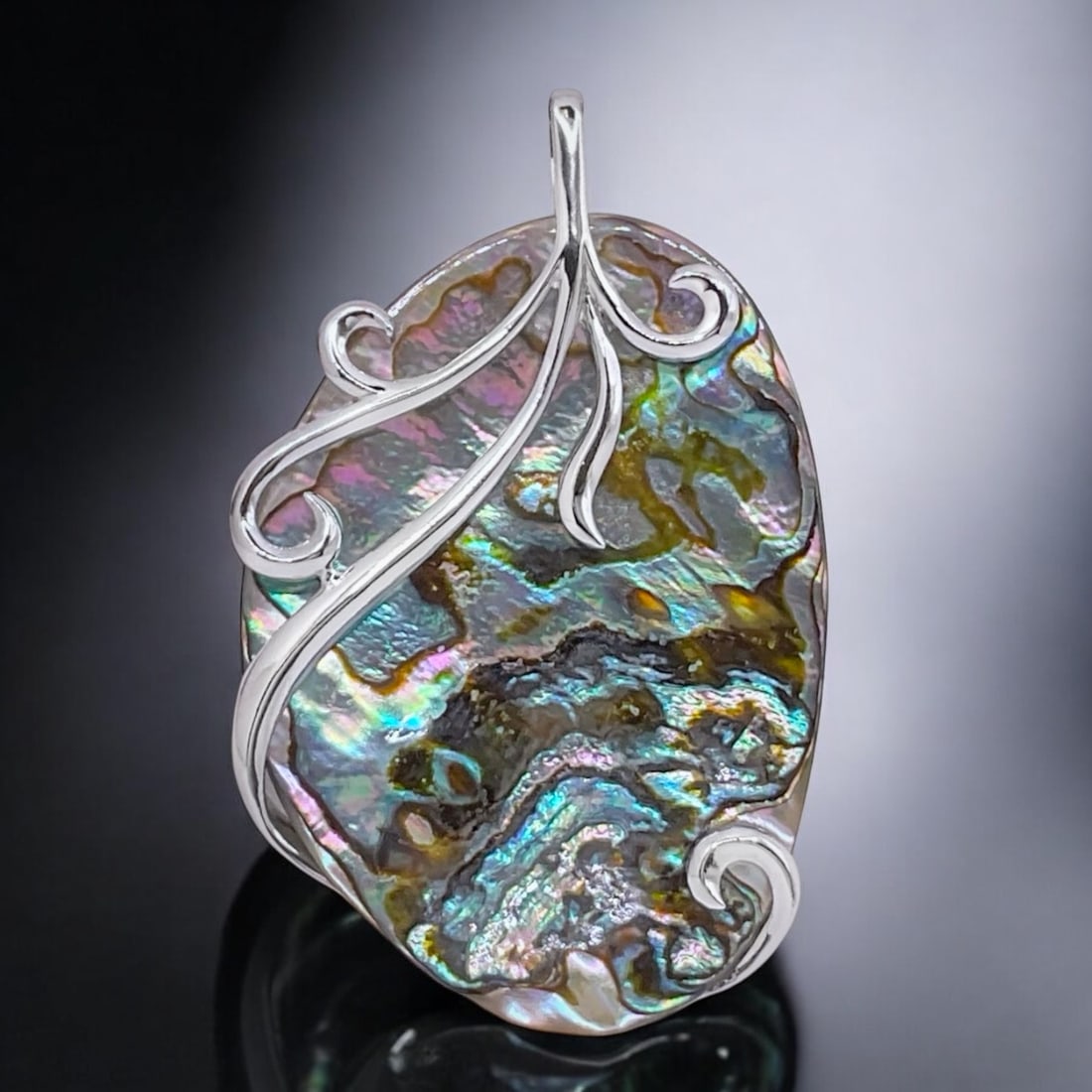 Large Abalone Pendant wrapped with a detailed Sterling Silver design: Product Details Item: Pendant Metal: Sterling Silver Gemstone: Abalone Approximate Measurements: 63.4 mm X 39.5 mm Ring Size: Not Applicable Chain Length: Not Applicable Chain Metal: