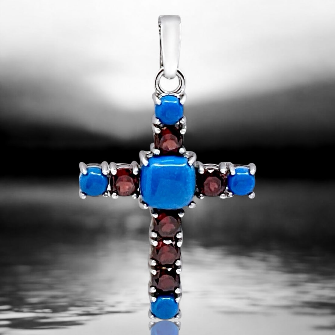 Spiritual Sterling Silver Cross Pendant with Blue Ceruleite & Garnet: Stabilized Ceruleite: One cushion shaped 9.5 mm cabochon and four round 5 mm cabochons Garnet: Six round modified-brilliant cut 5 mm Product Details Item: Pendant Metal: Sterling Silver Gemstone: Ceru