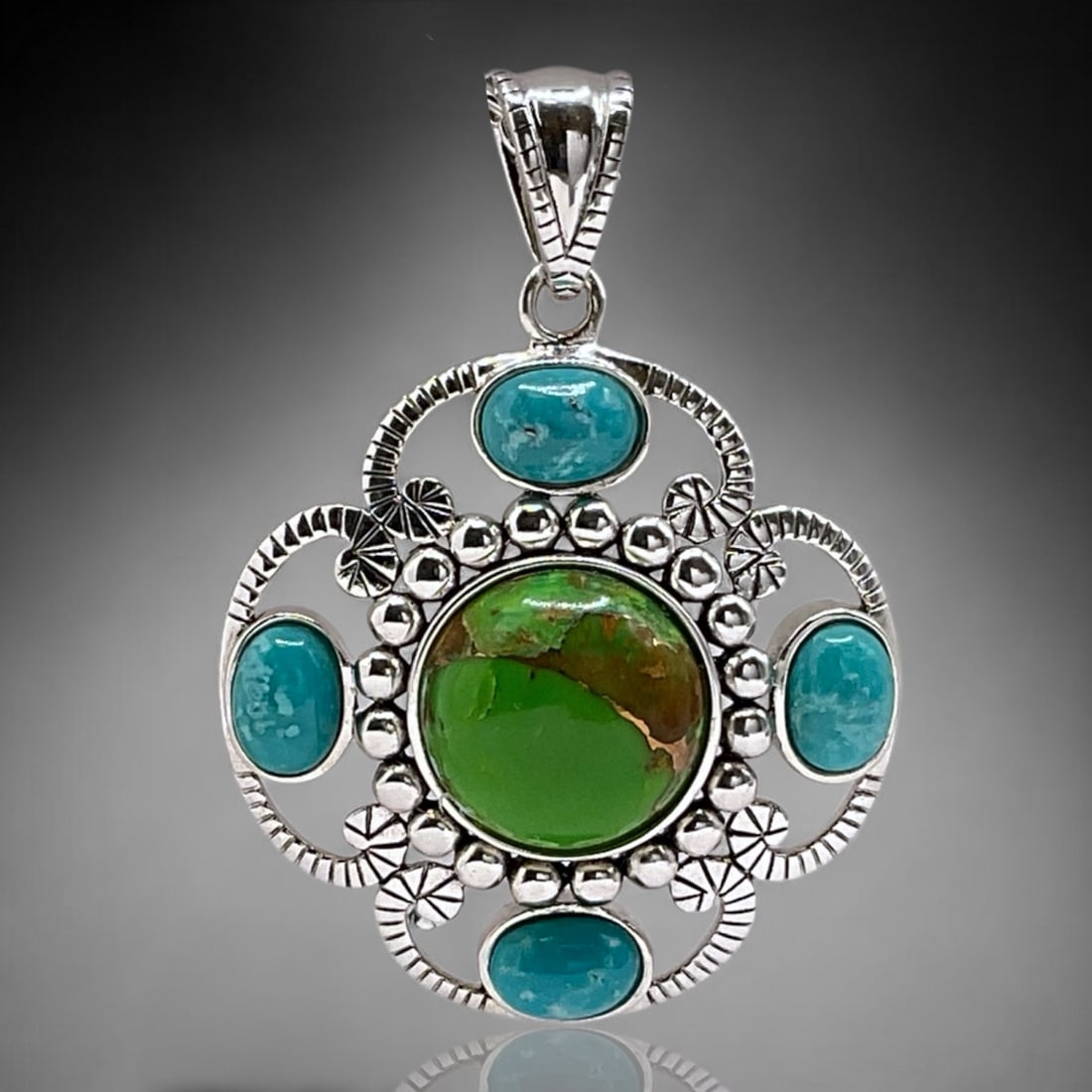 Green Mohave Turquoise Pendant with Campo Frio Turquoise in Sterling Silver: 14 mm round Green Mohave Four oval cut 7 mm X 5 mm Campo Frio turquoise cabachons Product Details Item: Pendant Metal: Sterling Silver Gemstone: Stabilized and Dyed Green Mohave Turquoise & Stabilized