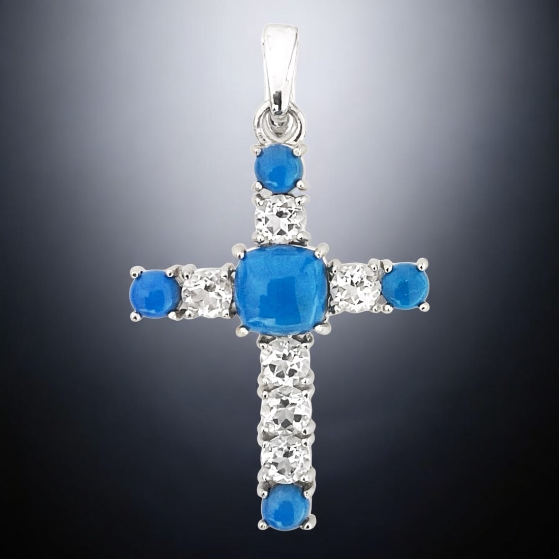 Southwest Cross with Ceruleite and White Topaz Accents: Stabilized Ceruleite: One cushion shaped 9.5 mm cabochon and four round 5 mm cabochons White Topaz: Six round modified-brilliant cut 5 mm Product Details Item: Pendant Metal: Sterling Silver Gemstone: