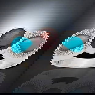 Sleeping Beauty Turquoise & Garnet Bow Ring with White Topaz accents - Size 8: Stabilized Sleeping Beauty Turquoise: Two pear shaped 7 mm X 4.5 mm cabochons Garnet: One round modified-brilliant cut 7 mm White Topaz: 12 round modified-brilliant cut 1.25 mm Product Details 