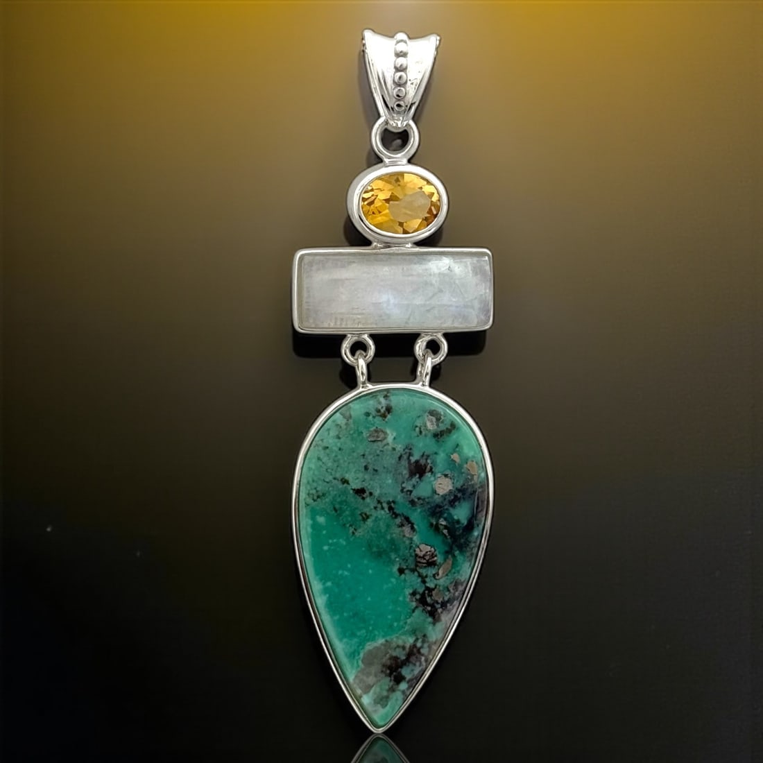 Enchanting Turquoise, Moonstone, & Citrine Sterling Silver Pendant: Turquoise (1) 38 mm X 21mm Moonstone (1) 21 mm X 7 mm Citrine (1) 9 mm X 7 mm Product Details Item: Pendant Metal: Sterling Silver Gemstone: Turquoise, Moonstone, & Citrine Approximate Measurements: 7