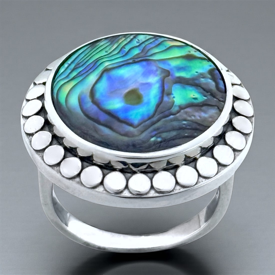 Brilliant round Abalaone Ring - Size 8 in Sterling Silver : 18mm round flat Abalone Cabochon Product Details Item: Ring Metal: Sterling Silver Gemstone: Abalone Approximate Measurements: Width: 24 mm Ring Size: 8 Chain Length: Not Applicable Chain M