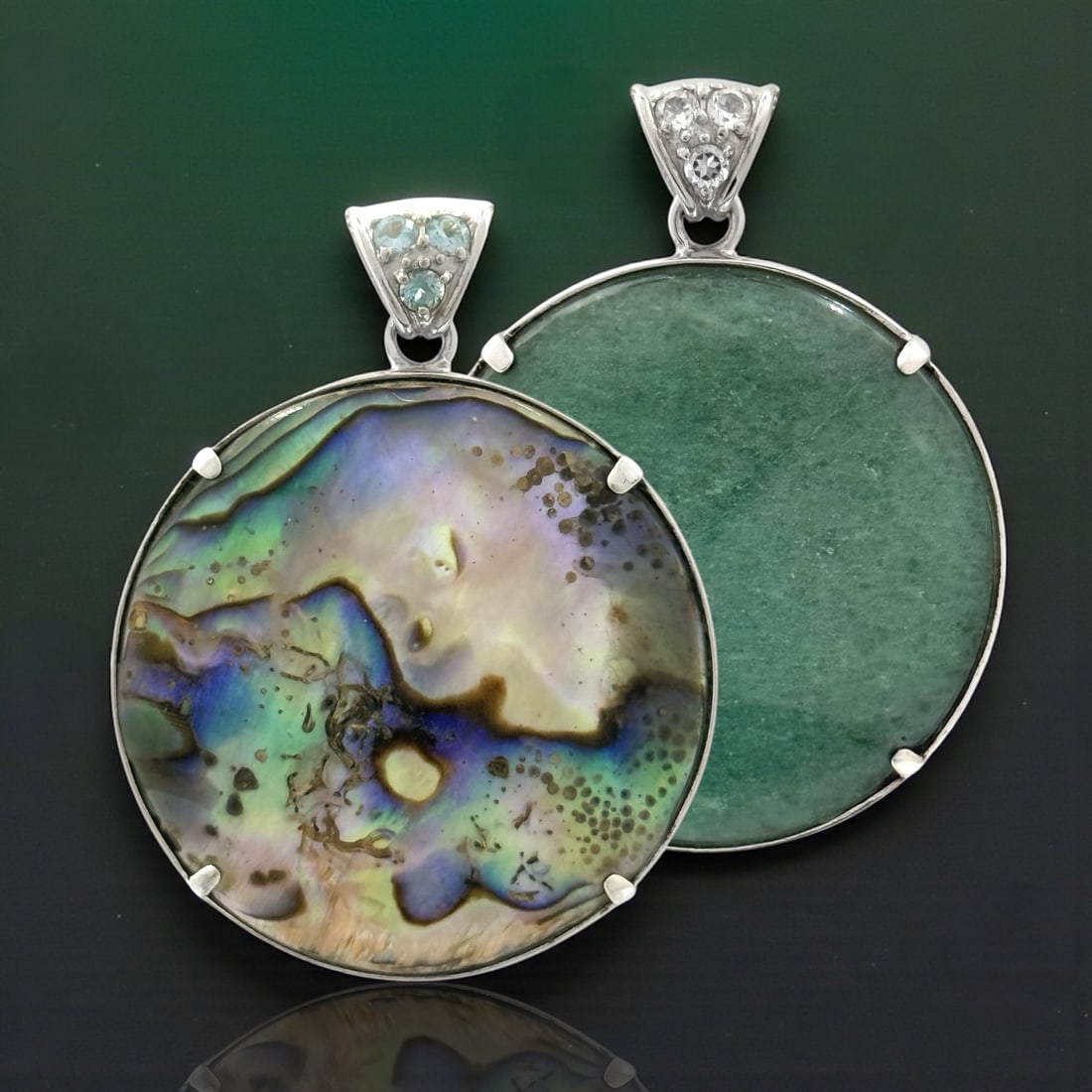Iridescent Reversible Abalone & Adventurine Circular Pendant: 40 mm Round Centerstones: Abalone & Green Adventurine 3 mm Blue Topaz & 3 mm White Topaz Product Details Item: Pendant Metal: Sterling Silver Gemstone: Adventurine, Abalone, Swiss Blue Topaz, White To