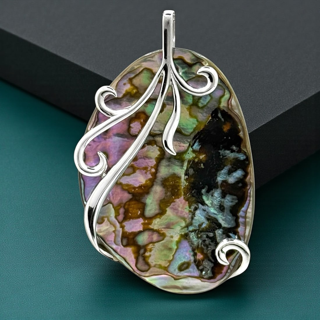 Abalone Pendant wrapped with a detailed Sterling Silver design: Product Details Item: Pendant Metal: Sterling Silver Gemstone: Abalone Approximate Measurements: 63.7 mm X 39.4 mm Ring Size: Not Applicable Chain Length: Not Applicable Chain Metal: Not