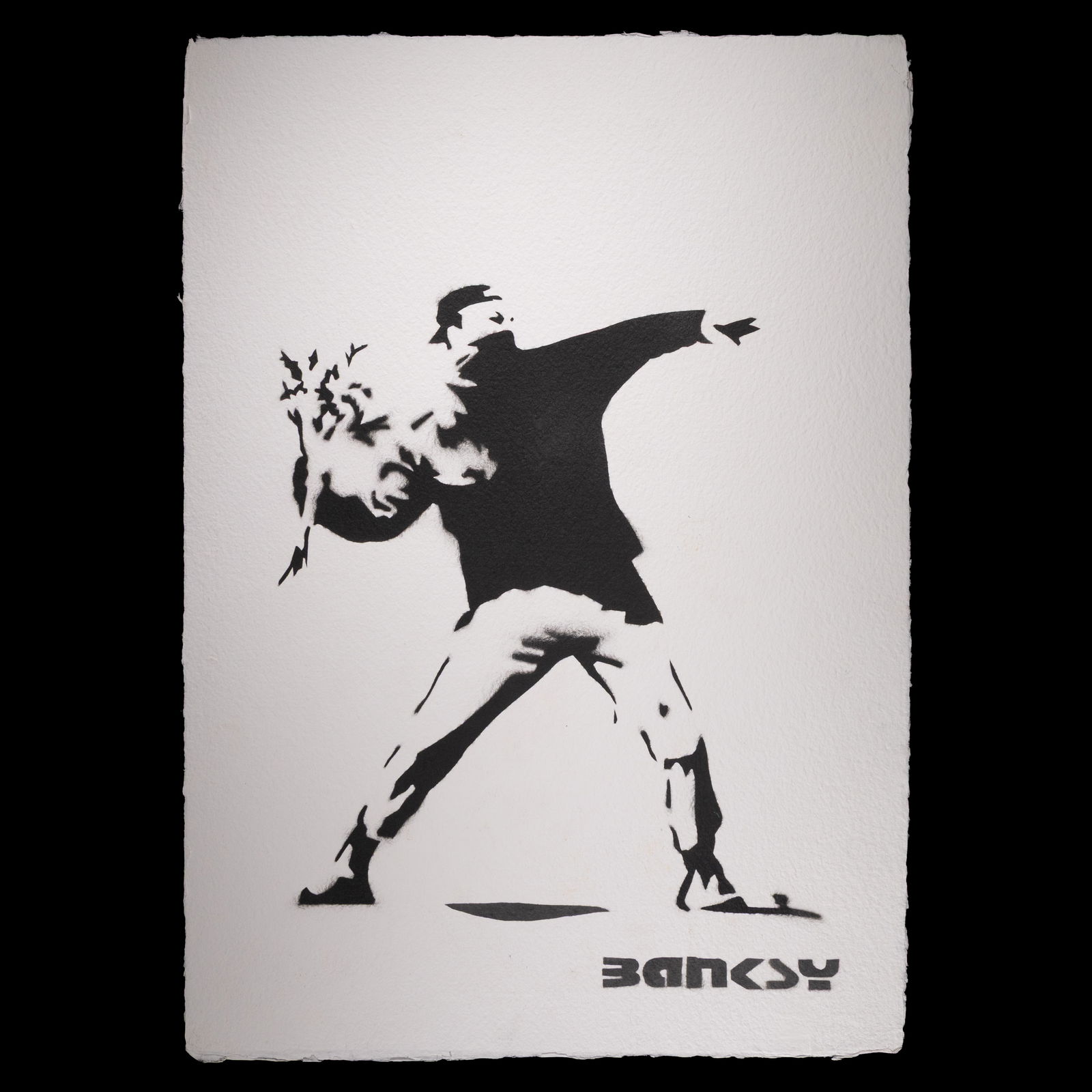 Banksy – “Love Is in the Air” (Flower Thrower): Title: Banksy – “Love Is in the Air” (Flower Thrower) – Black & White on Deckled Edge Paper Dimensions: 19.5 x 13.75 inches Medium: Black and White on Heavy Grade Deckled Edge Paper Frame: