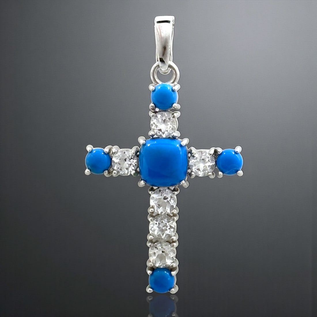 Southwest Cross with Ceruleite and White Topaz Accents: Stabilized Ceruleite: One cushion shaped 9.5 mm cabochon and four round 5 mm cabochons White Topaz: Six round modified-brilliant cut 5 mm Product Details Item: Pendant Metal: Sterling Silver Gemstone: