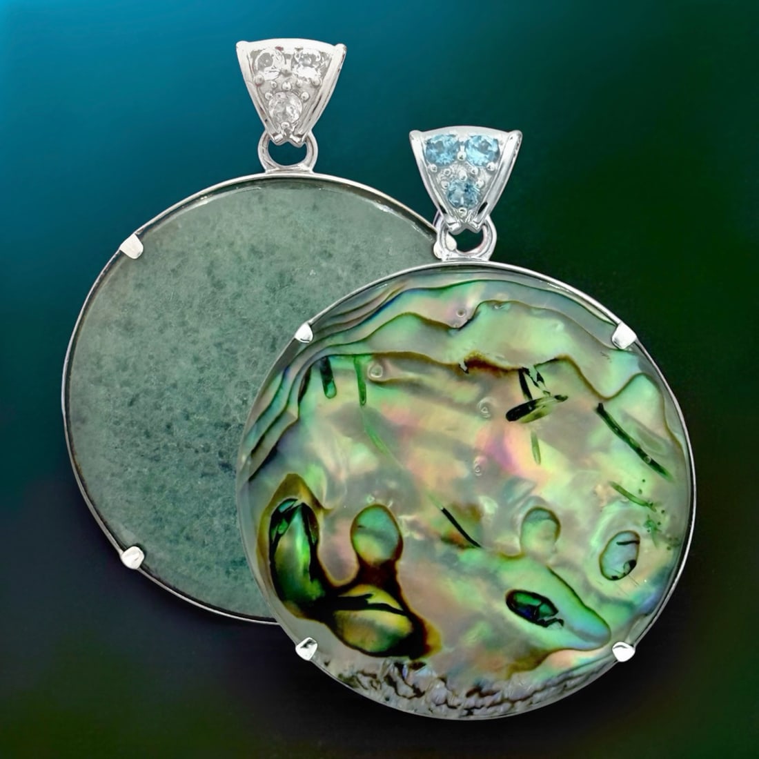 Iridescent Reversible Abalone & Adventurine Circular Pendant: 40 mm Round Centerstones: Abalone & Green Adventurine 3 mm Blue Topaz & 3 mm White Topaz Product Details Item: Pendant Metal: Sterling Silver Gemstone: Adventurine, Abalone, Swiss Blue Topaz, 