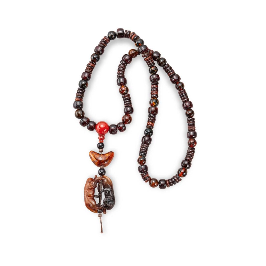 A BEADED AMBER NECKLACE WITH A COW-HORN CARVING OF TWIN