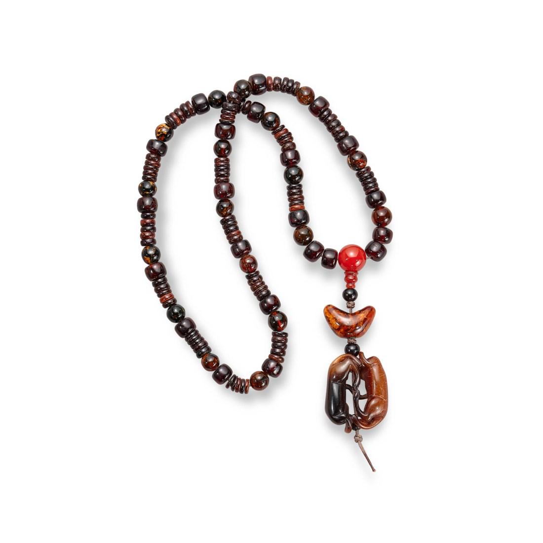 A BEADED AMBER NECKLACE WITH A COW-HORN CARVING OF TWIN