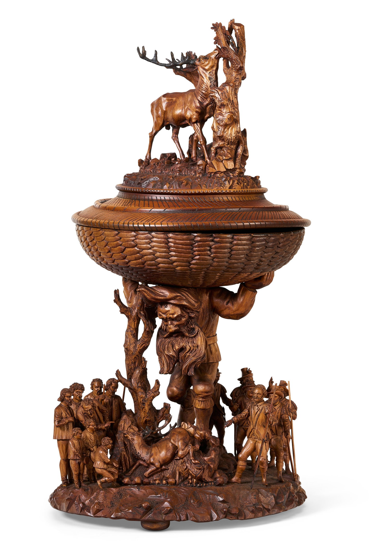 A GERMAN CARVED WALNUT HUNTING CUP AND COVER BY R. SCHAUERSEN, OBERAMMERGAU, DATED 1875: Details The cover surmounted by a ten-point stag, the basketweave cup supported by a crouched bearded giant and arb, the base with figures and a further stag, signed 'R. Schauersen. / Ober / mer / gau