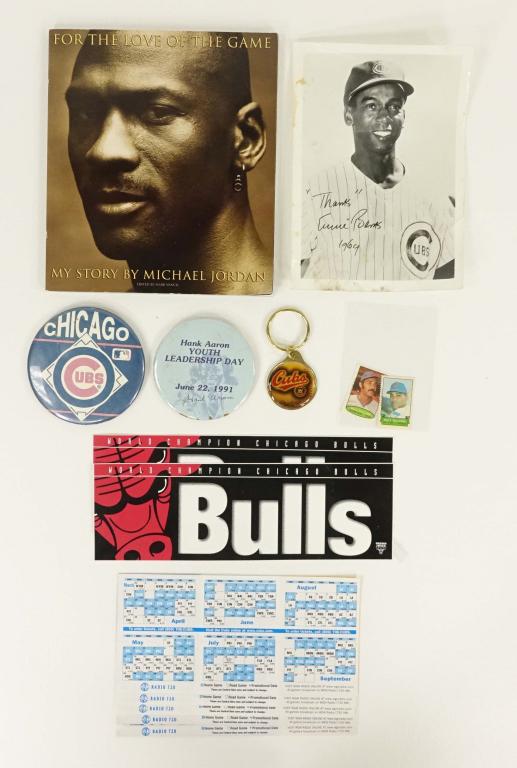 Chicago Sports Lot: 2003 Chicago Cubs pocket schedules (unfolded), buttons, stamps, keychain, Bulls bumper stickers, "For Love of the Game," B&W photo Ernie Banks (signed?).