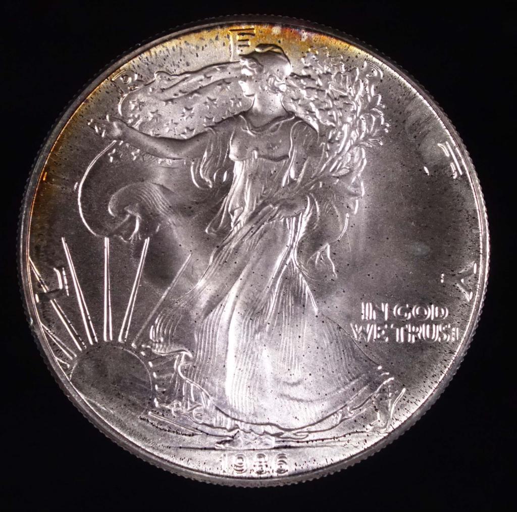 1986 Silver Eagle Bullion Coin: 1986 $1 Silver Eagle bullion coin. Gentle edge toning. 1 troy ounce of 0.999 fine silver. This was the first year of issue, and is a rarer date in the Silver Eagle series.