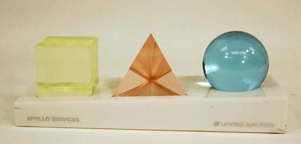 United Airlines Apollo Services Desk Advertising: Apollo Services and United Airlines marked advertising. Base is 11 x 3.75" and has cut outs in which are set a light yellow cube, light red (pink) pyramid and light blue sphere. Cube is 2.25", pyramid