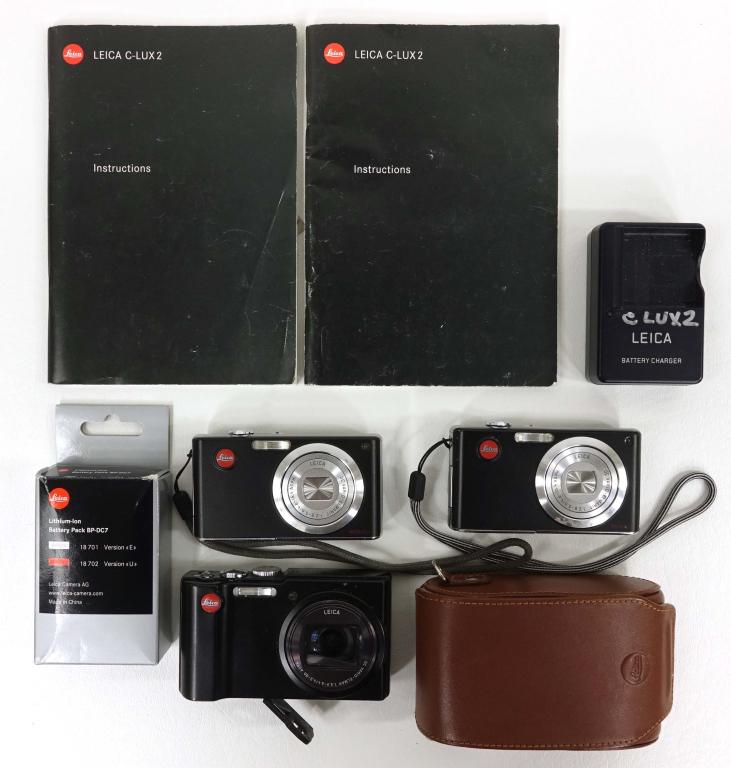 Leica Camera Lot (3): Three Leica Cameras: C-Lux 2 with two chargers, two batteries and instructions (2); V-Lux 40 with case. Battery compartment won't latch. Shutter open.