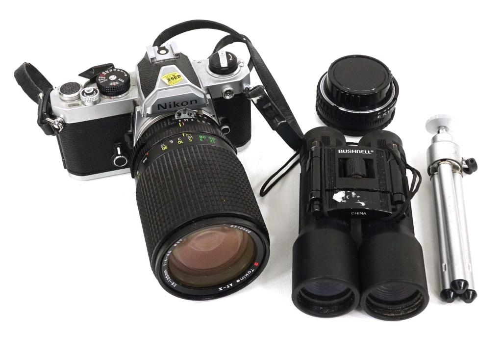 Nikon Camera Lot w/ Lenses: Includes: two lenses, Bushnell binoculars and portable tripod. Camera is a Nikon SLR Series E. 50mm 1:1.8 lens. Tokina AT-X 28-135mm 1:4-4.5 lens. Clean battery compartment. Shutter and curtain operat
