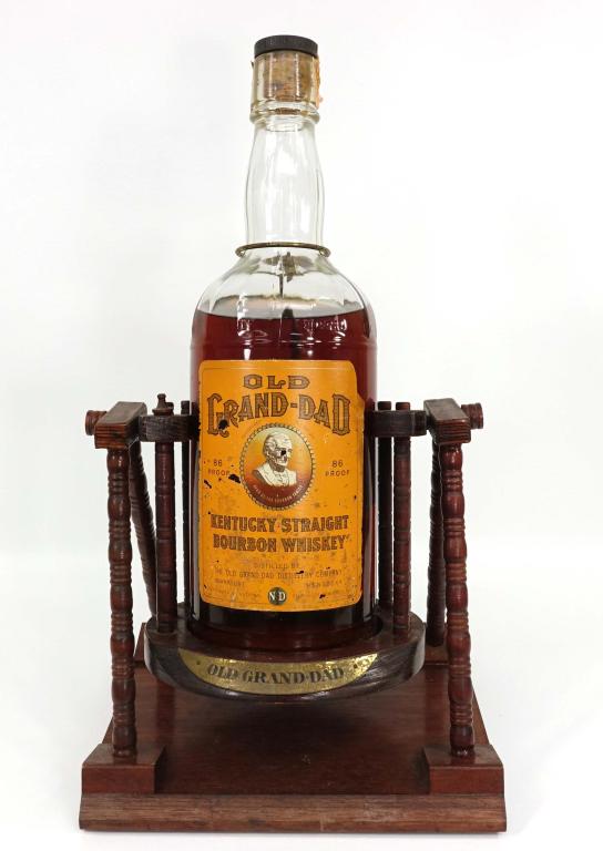1964 Old Grand Dad Bourbon Gallon Bottle: IF YOU MAY NEED SHIPPING YOU MUST SPEAK WITH IAN BEFORE BIDDING ON BOTTLES. Bourbon Whiskey. Broken seal. 1 gallon with wood cradle. 86 proof.