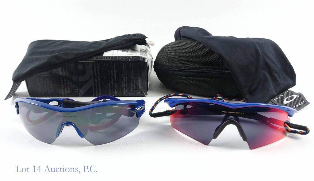 Oakley Sunglasses (2): Oakley Athletic Blue M Frame sunglasses with rainbow strap. In dust bag and case. Prizm lenses. Appear to be in good condition. Oakley "Radar" Blue sunglasses with blue / red / orange / yellow strap. 