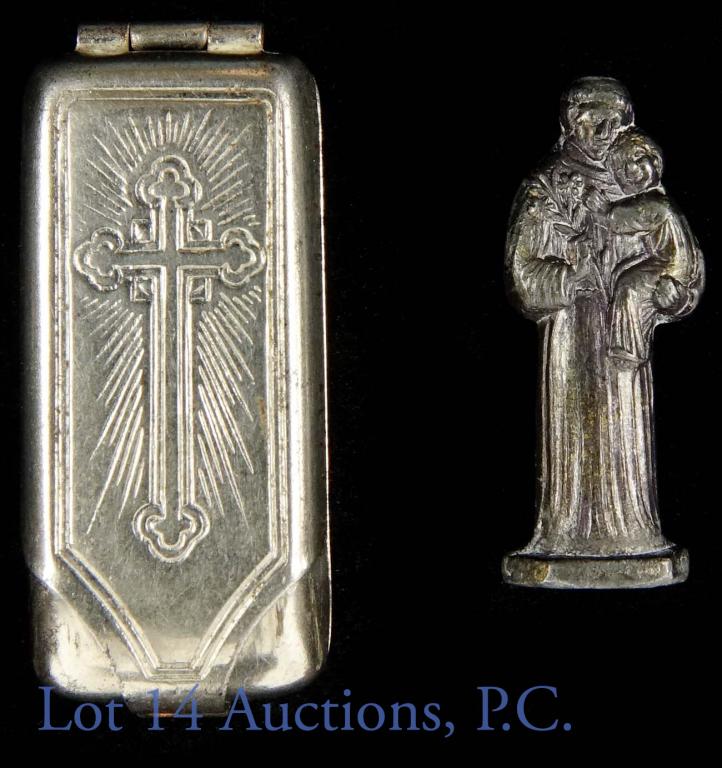 Saint Anthony German Miniature Figurine Locket: Silver colored hinged locket with suede backing. Dark metal miniature figurine of St. Anthony holding flowers and a child. Statue is approximately 1" tall. Both figurine and locket are stamped Germany