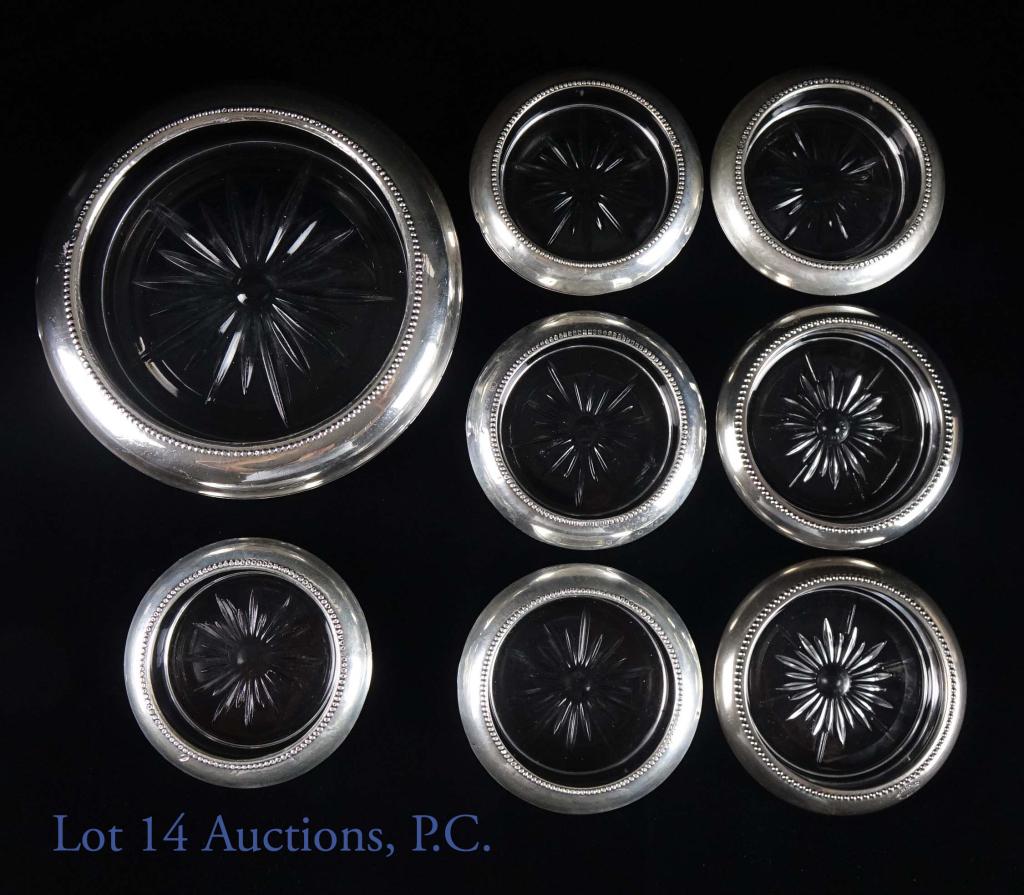 Sterling and Cut Glass Coasters (8): 8 sterling and cut glass coasters. 7 glass coasters, 1 bottle coaster. 3.75" diameter, 6.2 oz (glass). 6.75" diameter, 1.67 lbs (bottle).